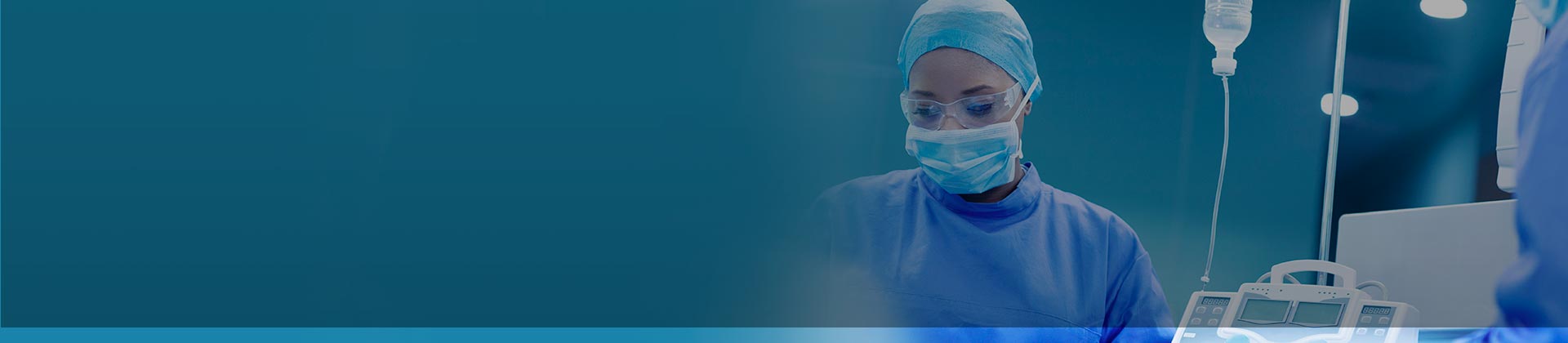 Travel nurse with mask over face and wearing blue scrubs in operating room.