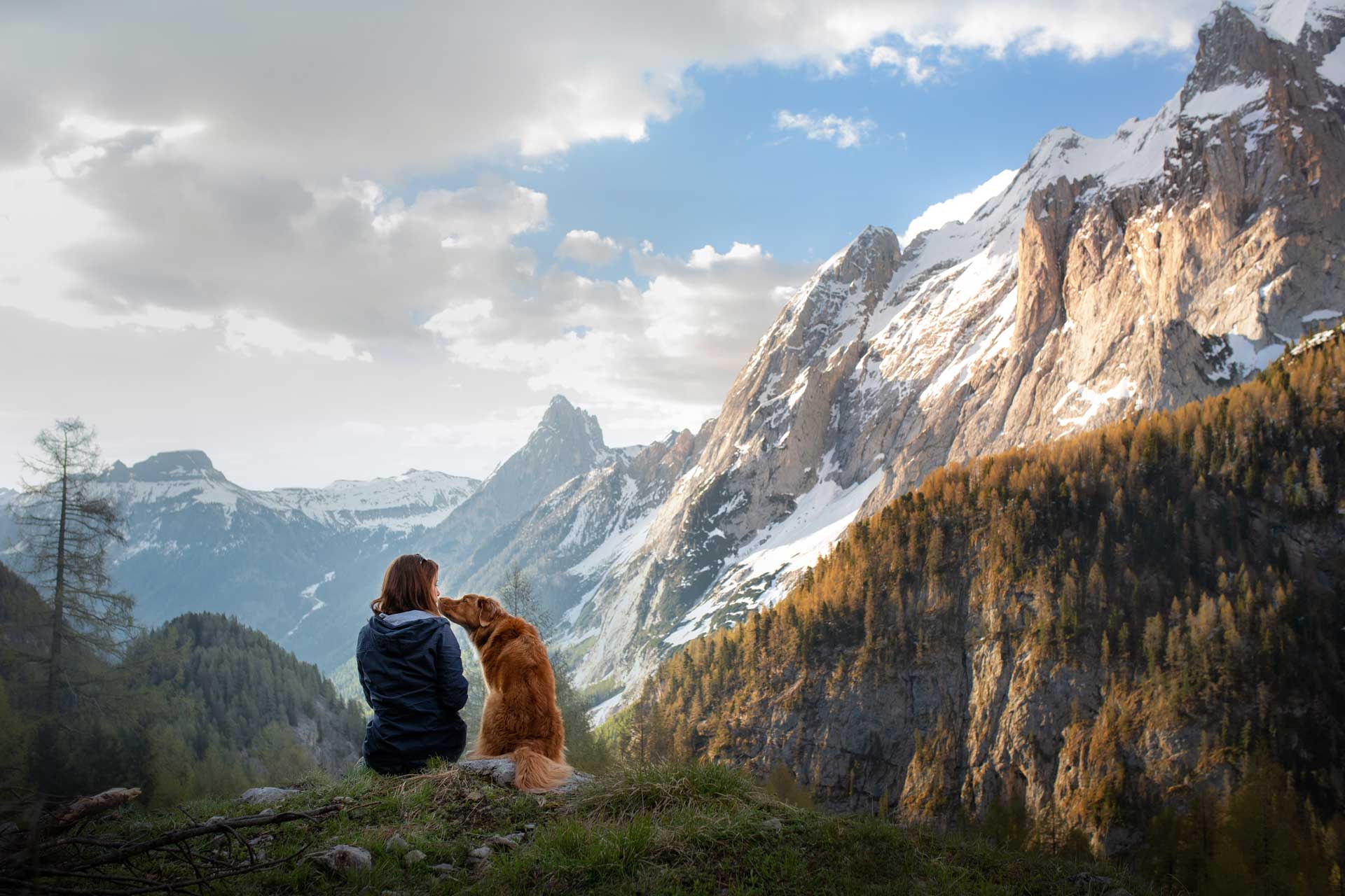 Dog licking woman's face in mountain setting
