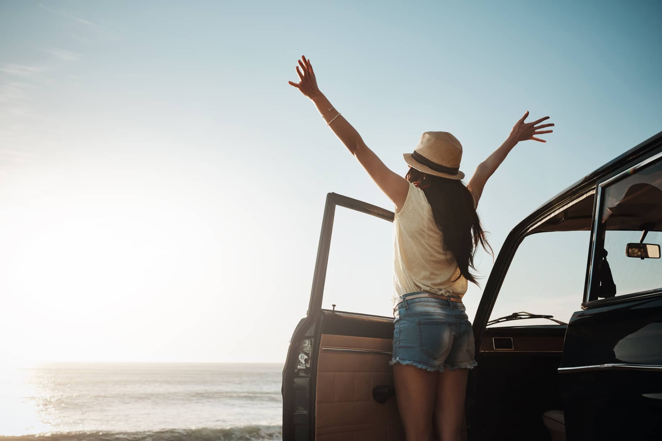 Travel nurse raising hands to the sky while soaking in the sun.
