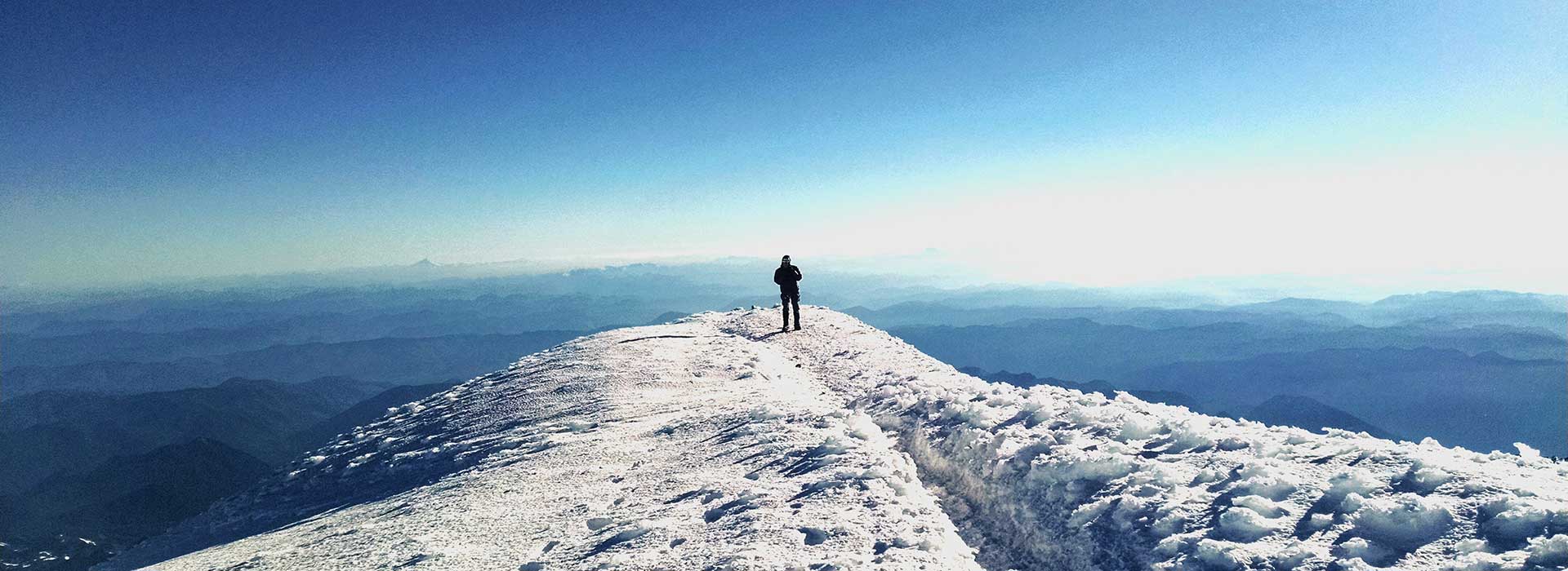 Person walking to edge of snowy peak Person walking to edge of snowy peak