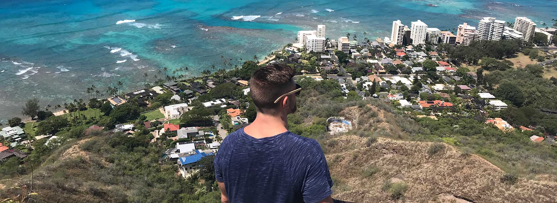 Man on mountain looking out over oceanside community Man on mountain looking out over oceanside community