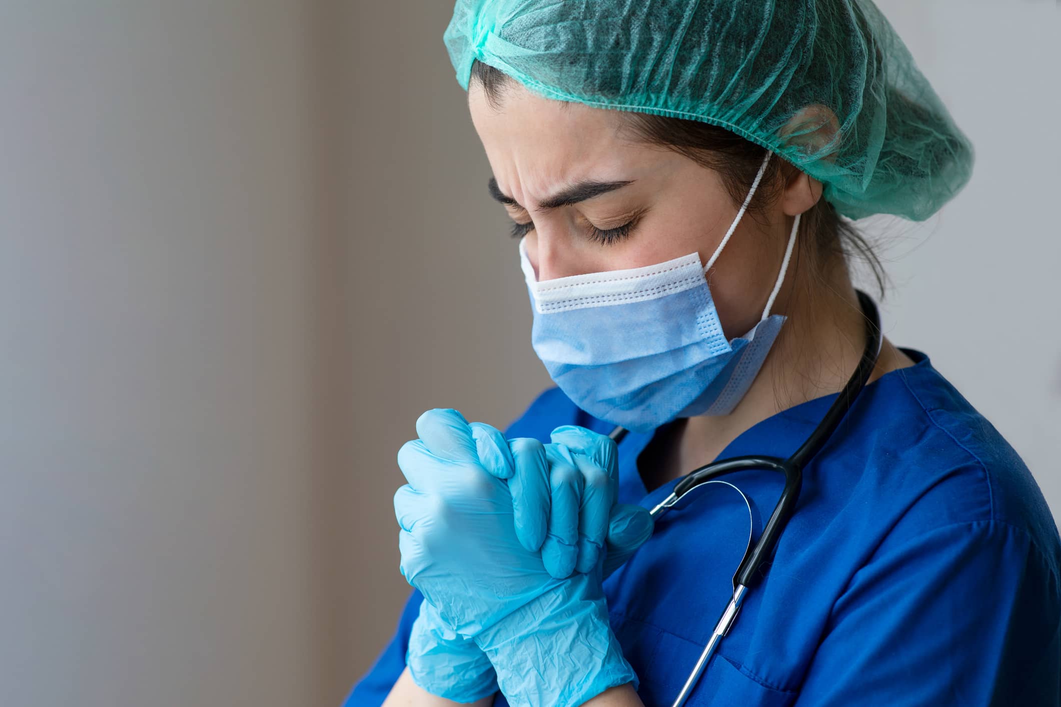 Exhausted nurse closing eyes and and clasping hands together as if in deep thought Exhausted nurse closing eyes and and clasping hands together as if in deep thought