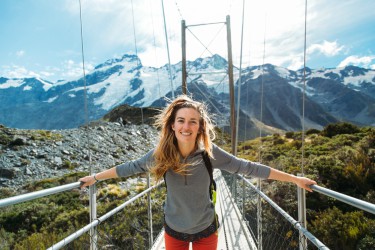 woman on wire pedestrian bridge with mountain behind woman on wire pedestrian bridge with mountain behind