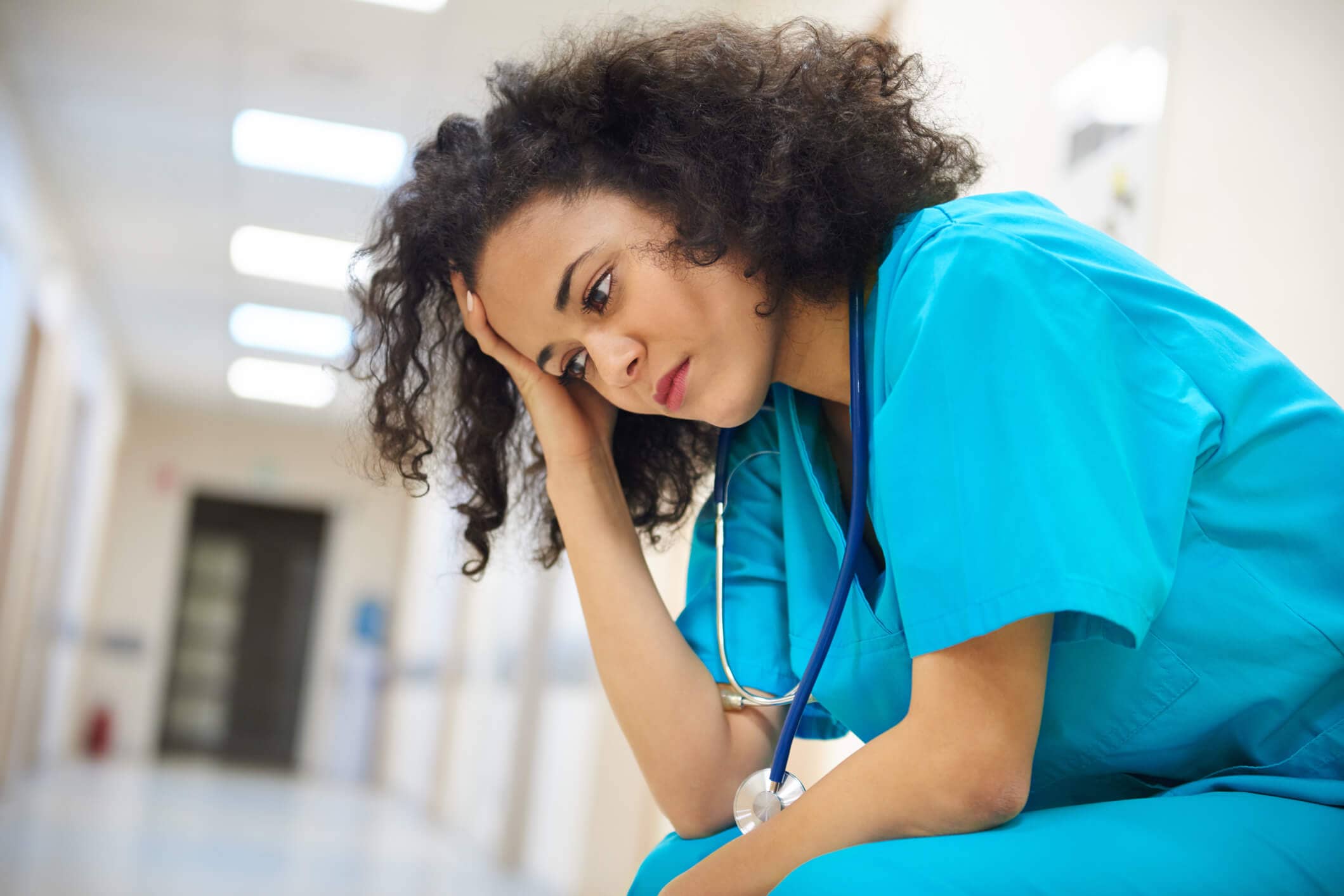 Tired stressed nurse with head in palm and elbows on knees Tired stressed nurse with head in palm and elbows on knees