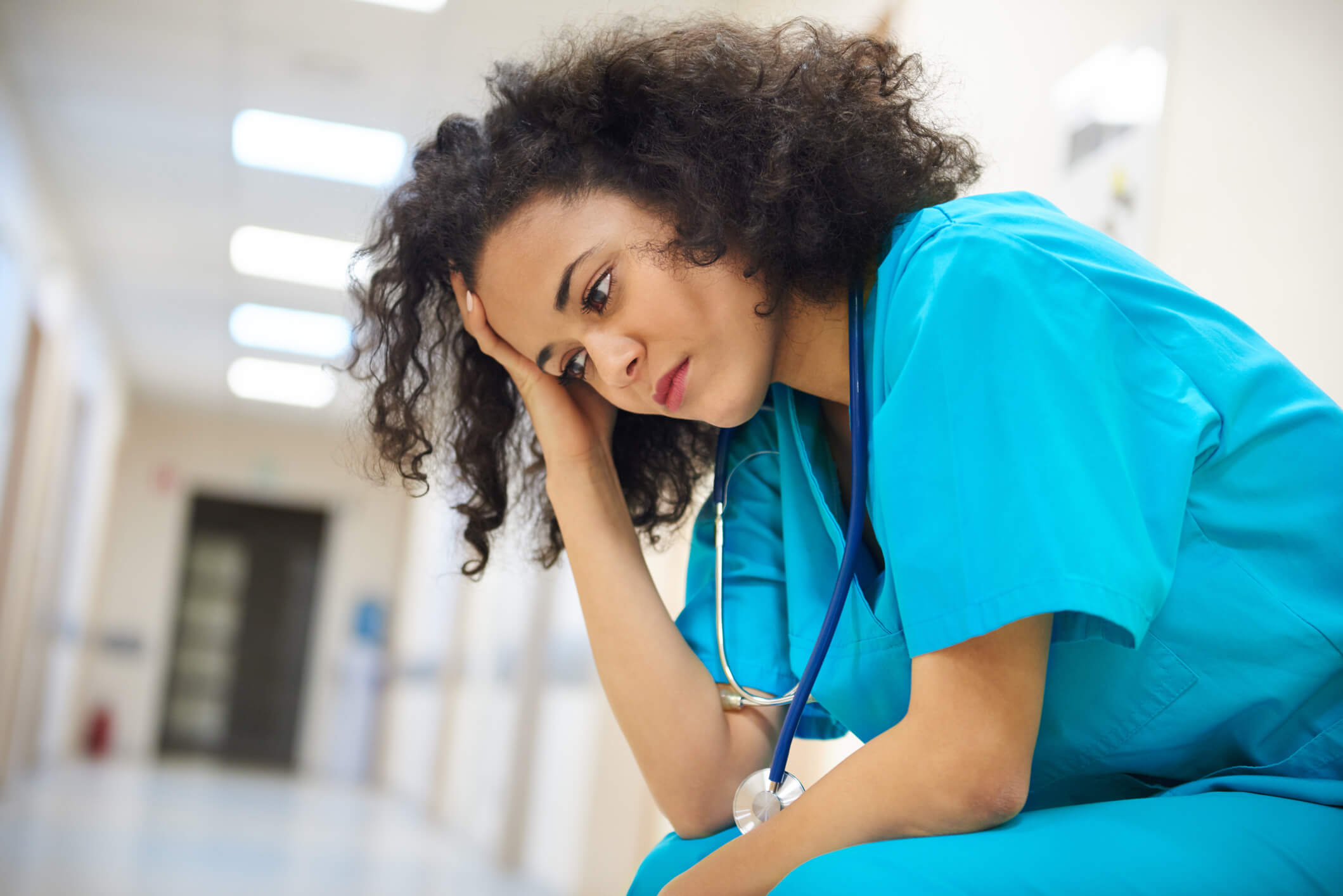 Tired stressed nurse with head in palm and elbows on knees Tired stressed nurse with head in palm and elbows on knees