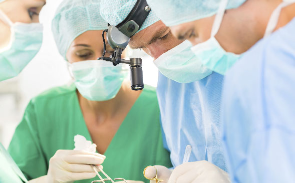 surgical professionals working, one with magnifying attachment surgical professionals working, one with magnifying attachment