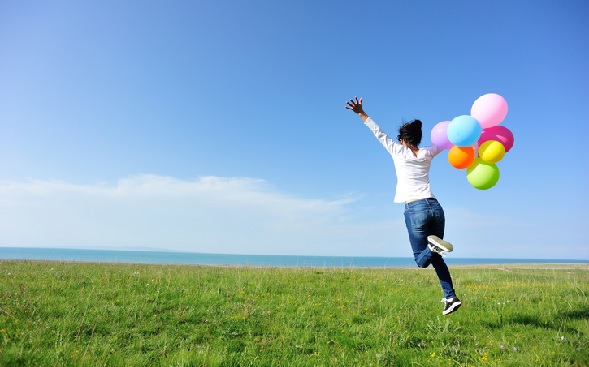 woman with bouquet of balloons in grassy field woman with bouquet of balloons in grassy field