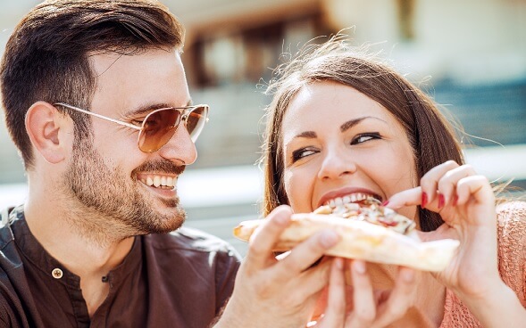 young couple sharing slice of pizza outdoors young couple sharing slice of pizza outdoors