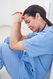 sad nurse sitting on floor of hospital hallway sad nurse sitting on floor of hospital hallway