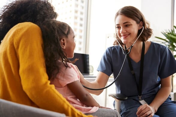 healthcare professional listening with stethoscope to child on her mother's lap healthcare professional listening with stethoscope to child on her mother's lap