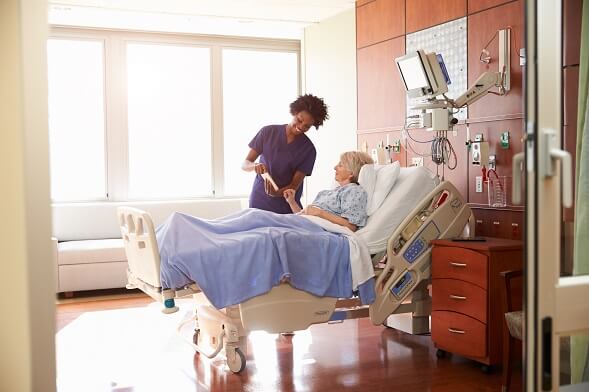 Bedside nurse showing something to senior patient in hospital bed Bedside nurse showing something to senior patient in hospital bed