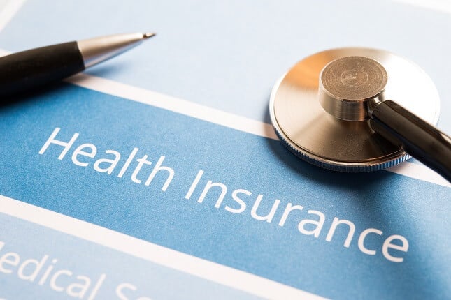 Close up of words Health Insurance with pen and stethoscope Close up of words Health Insurance with pen and stethoscope