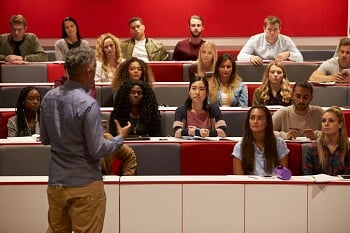 Instructor teaching class to students in theater seats Instructor teaching class to students in theater seats