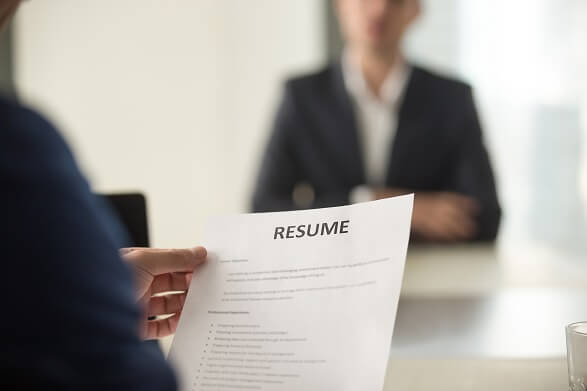 Job interview with man in foreground holding paper resume Job interview with man in foreground holding paper resume