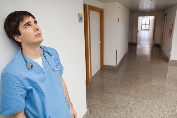Male nurse looking bleak, alone in hallway Male nurse looking bleak, alone in hallway