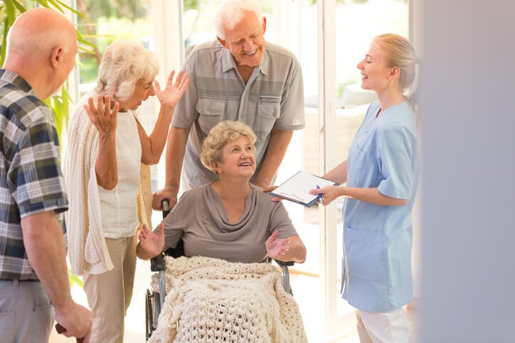 Nurse with senior patient in wheelchair and family standing around Nurse with senior patient in wheelchair and family standing around