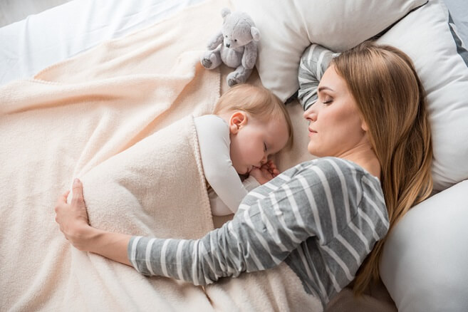 Mother and infant laying together in bed Mother and infant laying together in bed