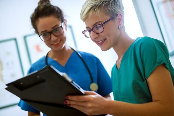 Two nurses reviewing information on a clipboard Two nurses reviewing information on a clipboard