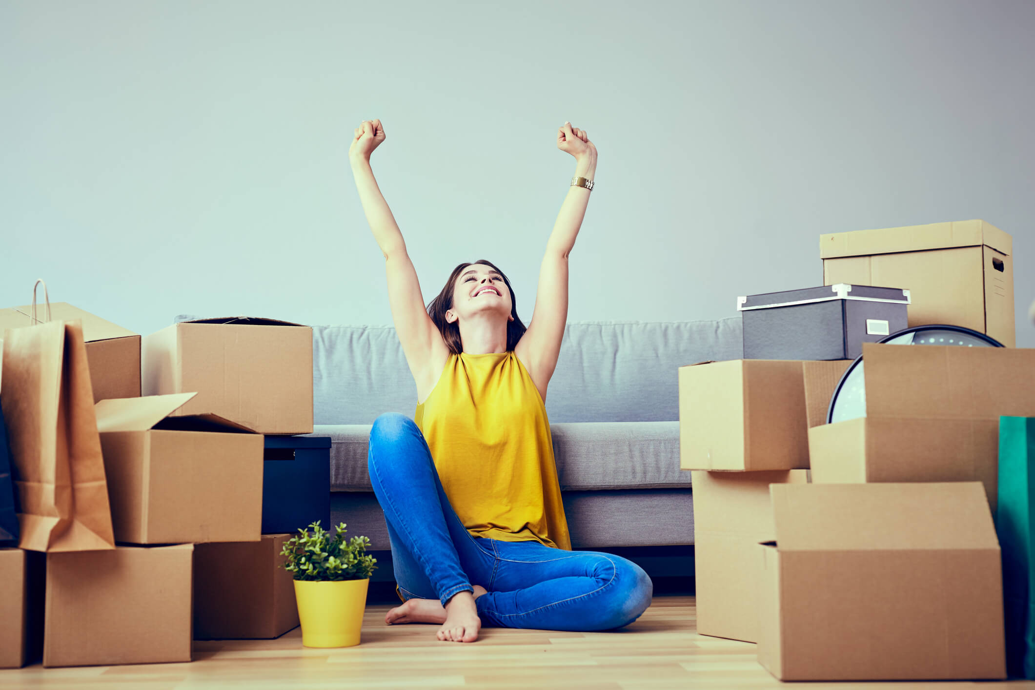 Woman surrounded by packing boxes with arms raised Woman surrounded by packing boxes with arms raised