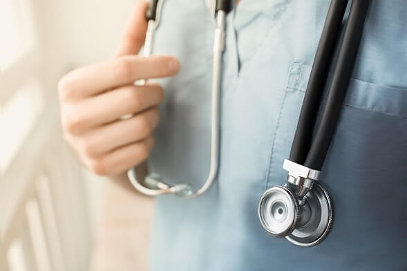 close up cropped image of hand on stethoscope against professional in scrubs close up cropped image of hand on stethoscope against professional in scrubs