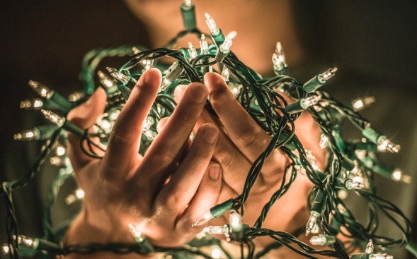hands holding tangle of white christmas lights hands holding tangle of white christmas lights