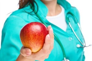 healthcare provider with stethoscope holding out an apple healthcare provider with stethoscope holding out an apple