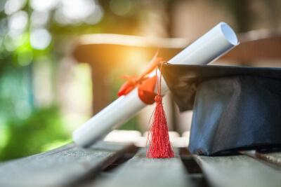 graduation cap and diploma sitting in pretty sunlight