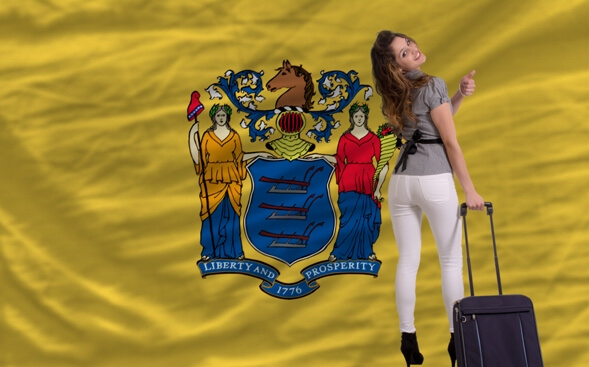 woman pulling suitcase in front of New Jersey state flag woman pulling suitcase in front of New Jersey state flag