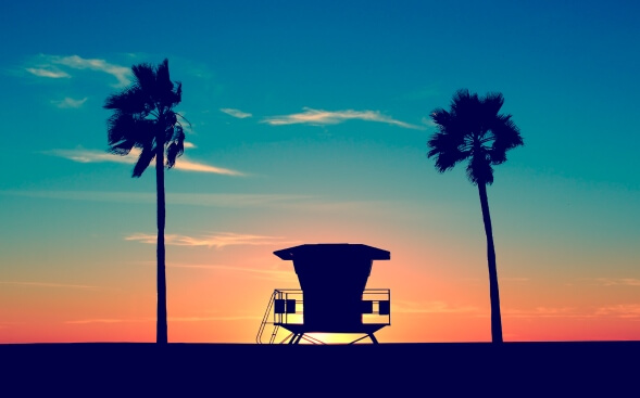 lifeguard tower framed by palm trees at sunset in California lifeguard tower framed by palm trees at sunset in California