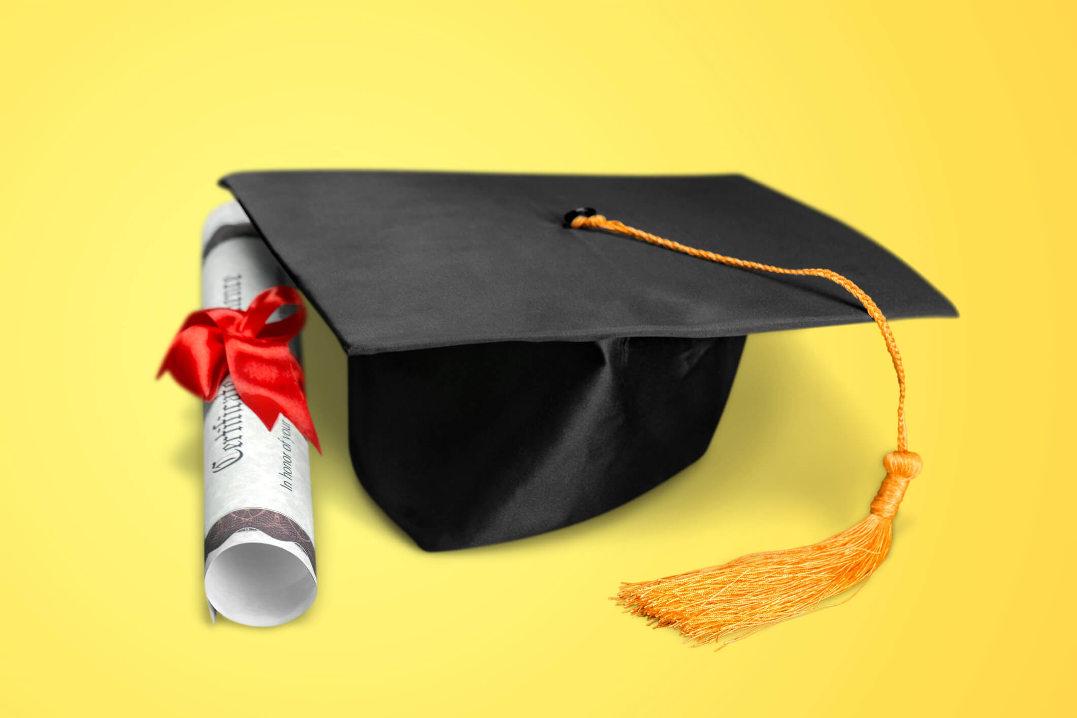 Graduation cap and diploma on yellow background Graduation cap and diploma on yellow background