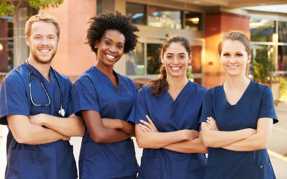 4 smiling young healthcare professionals facing camera with arms crossed 4 smiling young healthcare professionals facing camera with arms crossed
