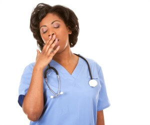 Tired healthcare professional with stethoscope yawning Tired healthcare professional with stethoscope yawning