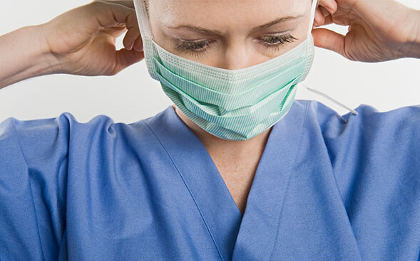 Nurse in Scrubs putting on a paper mask Nurse in Scrubs putting on a paper mask