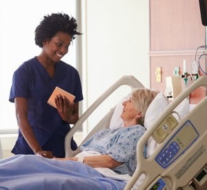 nurse standing bedside talking to patient nurse standing bedside talking to patient
