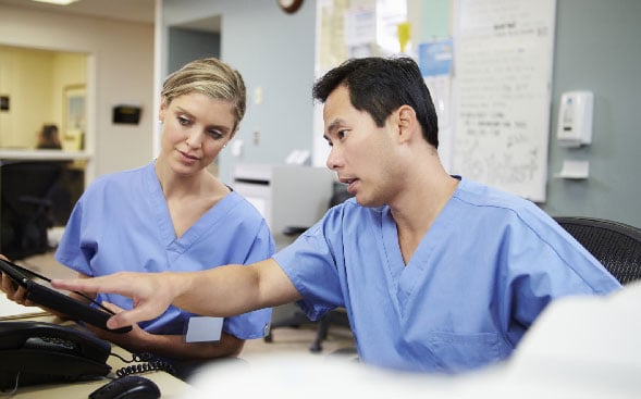 two nurses working together, one pointing to computer screen two nurses working together, one pointing to computer screen