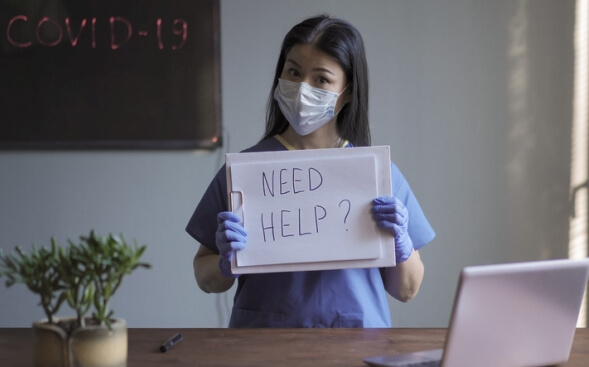 masked nurse holding up need help sign masked nurse holding up need help sign