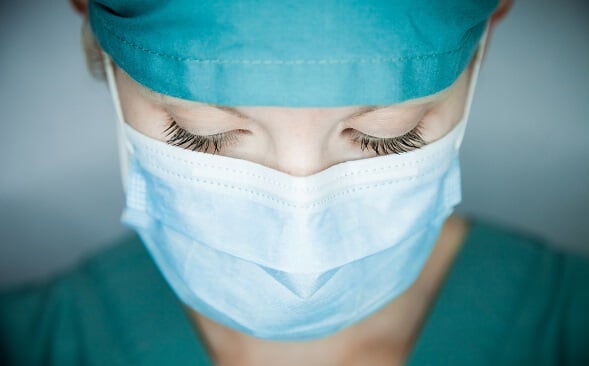 close up of nurse face wearing mask with eyes cast down close up of nurse face wearing mask with eyes cast down