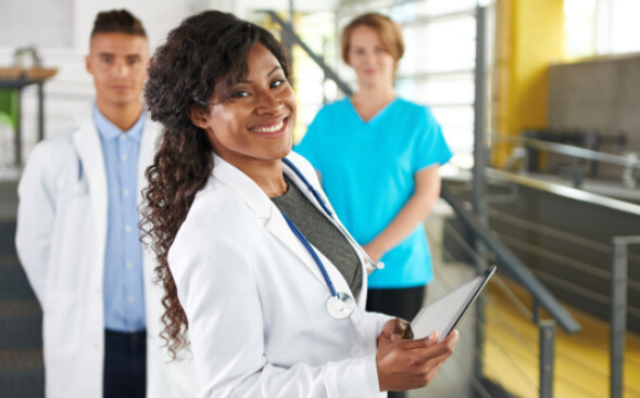 smiling healthcare professionals with 2 colleagues standing behind smiling healthcare professionals with 2 colleagues standing behind