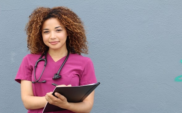 nurse holding clipboard looking at camera nurse holding clipboard looking at camera