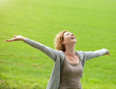 woman with arms spread and head thrown back in grassy field woman with arms spread and head thrown back in grassy field