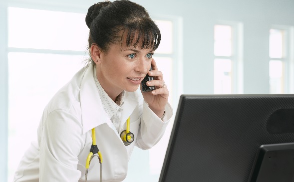 healthcare professional talking on phone and looking at computer healthcare professional talking on phone and looking at computer