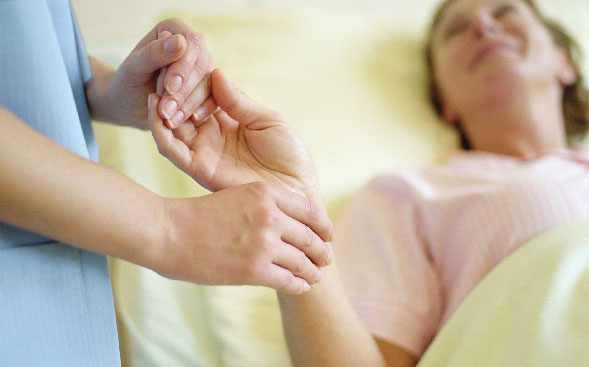 Close up of nurse holding hand of patient in bed Close up of nurse holding hand of patient in bed