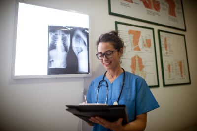 Nurse looking at file standing next to scan display Nurse looking at file standing next to scan display