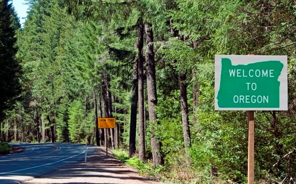Welcome to Oregon road sign on tree lined road Welcome to Oregon road sign on tree lined road