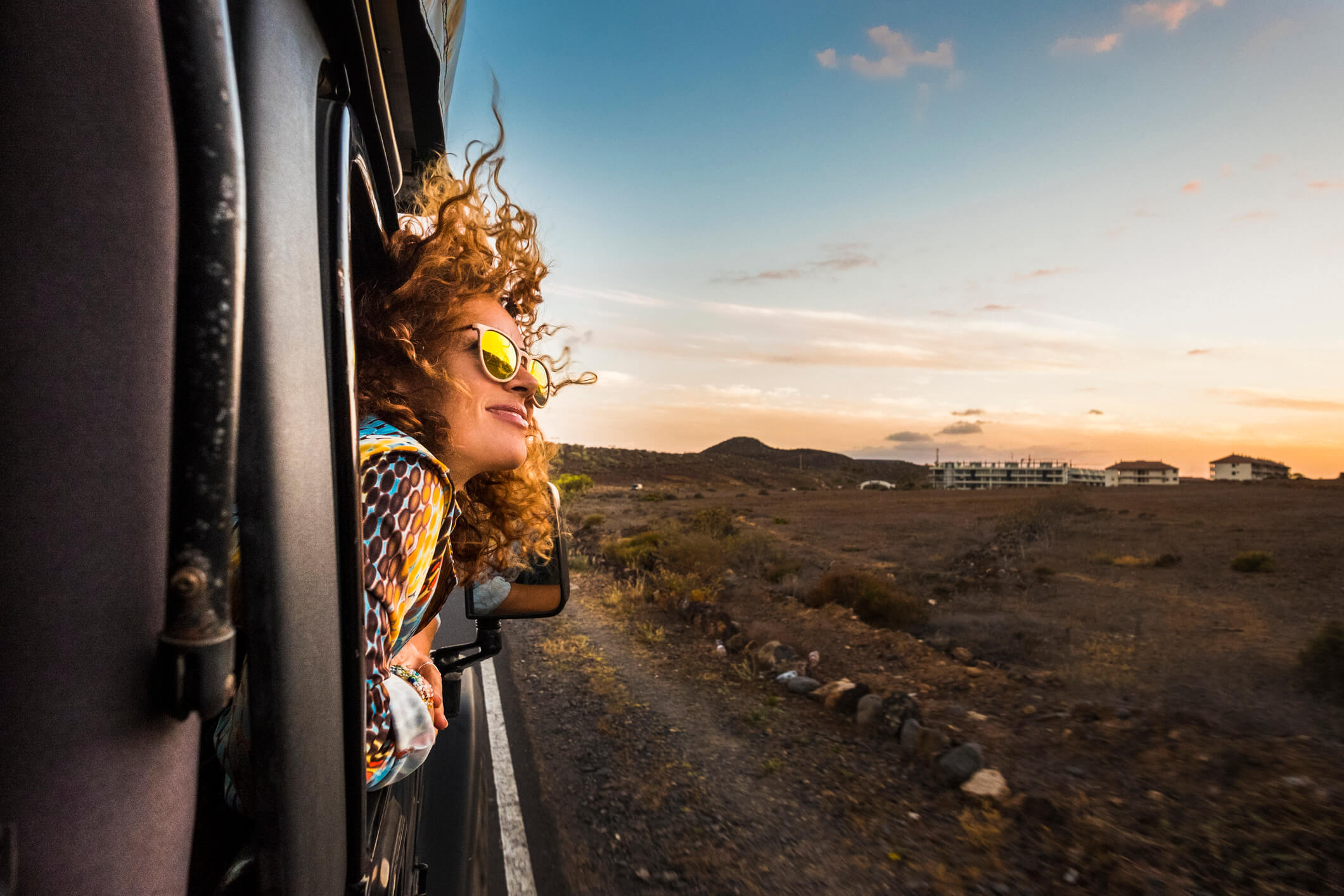 woman in sunglasses enjoying wind with her head out car window woman in sunglasses enjoying wind with her head out car window