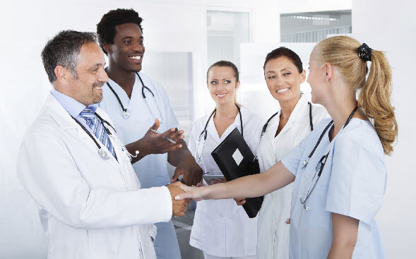 group of healthcare professionals with two shaking hands group of healthcare professionals with two shaking hands