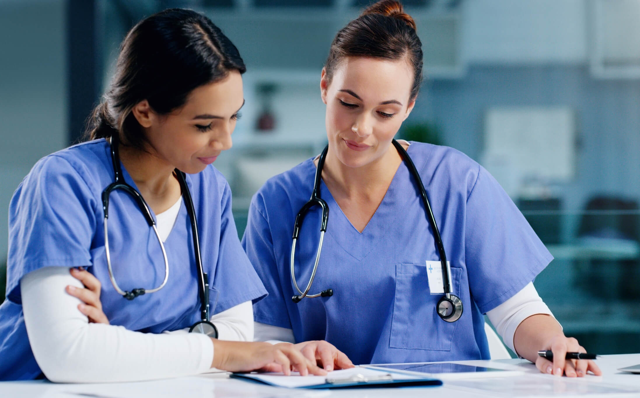 two nurses looking at paperwork at nurses station two nurses looking at paperwork at nurses station