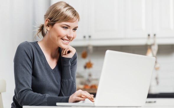 smiling woman at home looking at laptop smiling woman at home looking at laptop