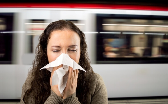 woman sneezing in underground train station woman sneezing in underground train station