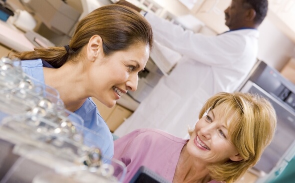 Two nurses smiling, enjoying each other, at nurses station Two nurses smiling, enjoying each other, at nurses station